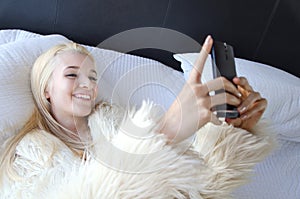 Young lady laying on a bed laughing and taking a selfie