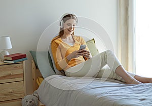 Young Lady Listening To Songs In Earphones Using Cellphone Indoors