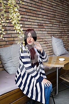 Young lady with long hair sitting alone in street cafe