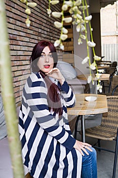 Young lady with long hair sitting alone in street cafe