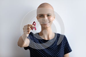 Young lady with oncology look at camera hold scarlet ribbon