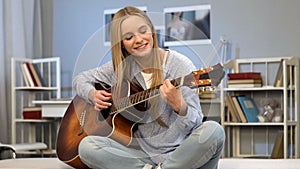 Young lady playing guitar in her room, writing song, dreaming of music career