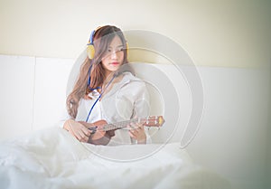 Young lady playing Ukulele in her bedroom.