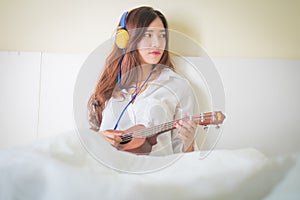 Young lady playing Ukulele in her bedroom.