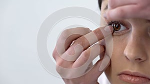 Young lady putting contact lens in eye, eyesight and hygiene, face closeup