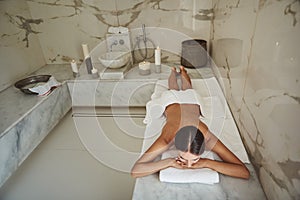 Young lady putting her chin on the hands while lying on her stomach in hammam