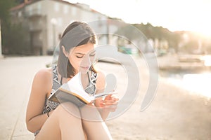 Young lady reading a book on a beach at sunset