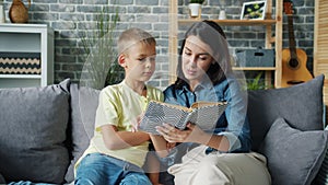 Young lady reading fairy-tale to cute boy educating child at home indoors
