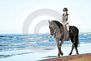 Young Lady riding horseback at wavy seaside/ocean coast