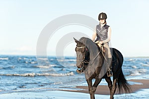 Young Lady riding horseback at wavy seaside/ocean coast