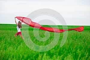 Young lady runing with tissue in green field. Woman with scarf.