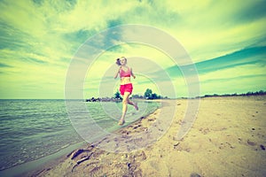 Young lady running at the sunny summer sand beach