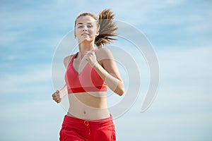 Young lady running at the sunny summer sand beach. Workout. Jog