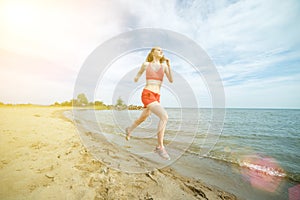 Young lady running at the sunny summer sand beach. Workout. Jog