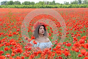 Young lady sitiing in poppies