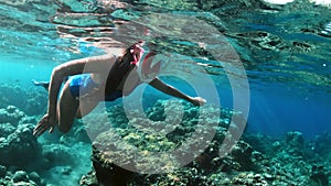Young lady snorkeling over coral reefs in a tropical sea. Woman with mask snorkeling in clear water