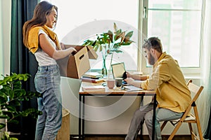 Young lady stand with box next to working husband