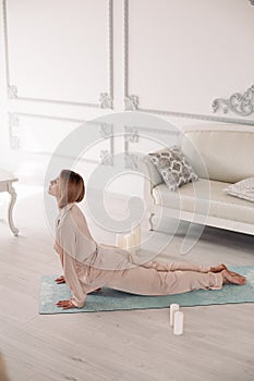 Young lady starting morning with yoga exercises in bedroom