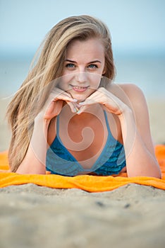 Young lady sunbathing on a beach. Beautiful woman posing at the