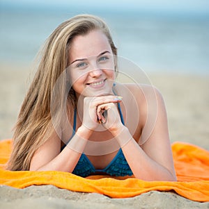 Young lady sunbathing on a beach. Beautiful woman posing at the