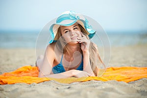 Young lady sunbathing on a beach. Beautiful woman posing at the