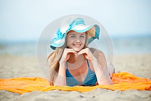 Young lady sunbathing on a beach. Beautiful woman posing at the