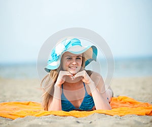 Young lady sunbathing on a beach. Beautiful woman posing at the