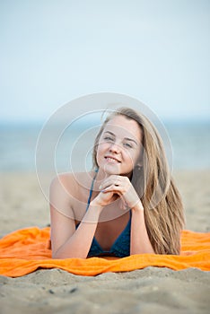 Young lady sunbathing on a beach. Beautiful woman posing at the