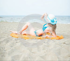 Young lady sunbathing on a beach. Beautiful woman posing at the