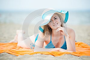 Young lady sunbathing on a beach. Beautiful woman posing at the