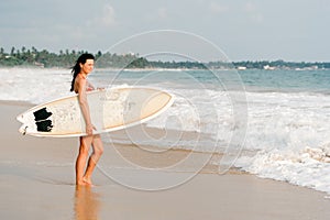 Young lady surfer standing on the beach with surf board.