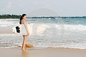 Young lady surfer standing on the beach with surf board