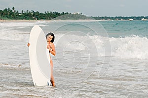 Young lady surfer standing on the beach with surf board