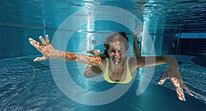 Young lady swimming underwater in the pool