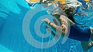 Young lady swimming underwater in the pool. Underwater woman portrait in swimming pool