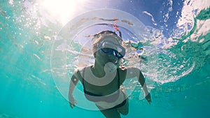 Young lady is swimming underwater in the sea