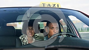 Young lady talking to taxi driver while sitting at backseat in the car. Yellow taxi car roof sign. People, job, service