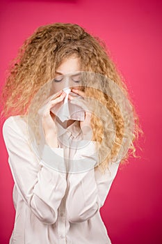 Young lady with unruly hair sneezing to the handkerchief