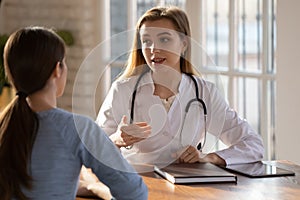 Young lady visiting attentive female doctor at modern medical center