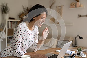 Young lady wave hand joining to virtual event using pc