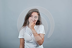 Young lady in white t-shirt over isolated wall holds her palm near her mouth