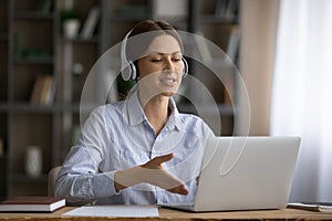 Young lady in wireless earphones speak by computer screen