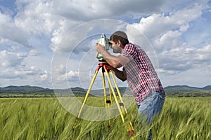 Young land surveyor in a wheat field