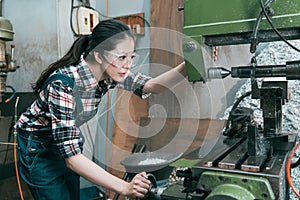 Young lathe company woman worker wearing goggles