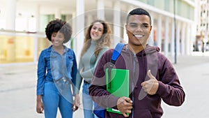 Young latin american male student with backpack and group of international students