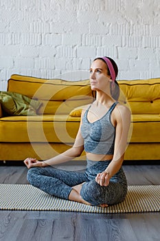 A young Latin American woman does yoga at home. Athletically built young woman stretches out in the living room of a beautiful