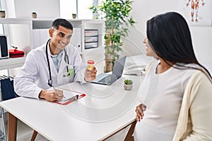 Young latin couple doctor and patient having medical session holding urine test tube at clinic