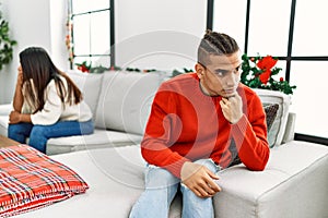Young latin couple on problems with sad expression sitting on the sofa at home