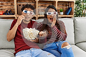 Young latin couple scared watching movie using 3d glasses at home