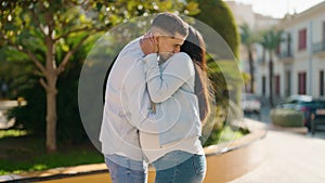 Young latin couple smiling confident hugging each other and kissing at park